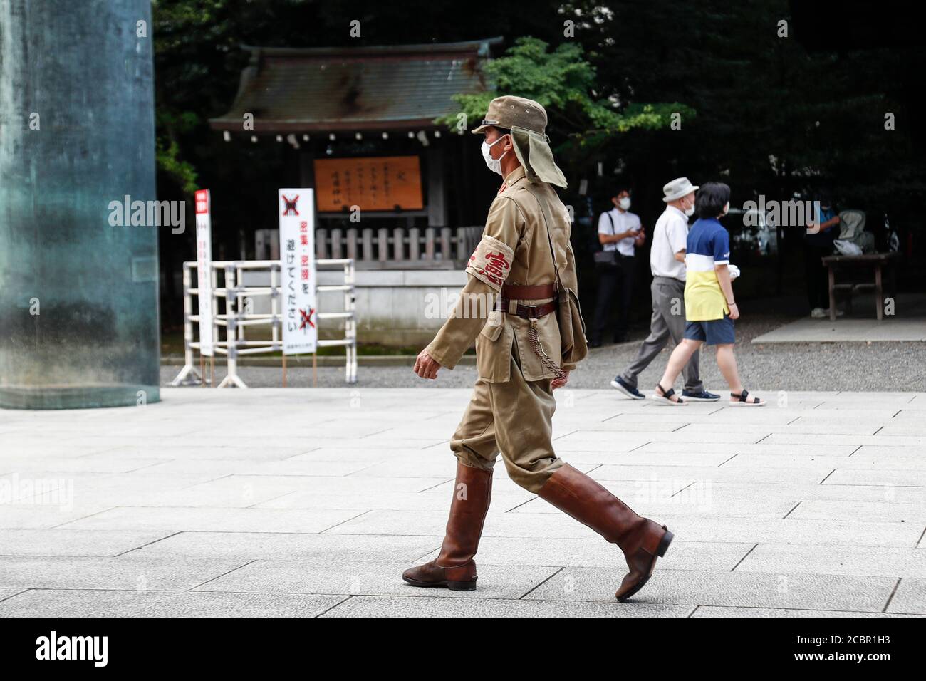 Tokyo, Japan. 15th Aug, 2020. A man dressed as a Japanese imperial army soldier is seen waiting to the Yasukuni Shrine during the 75th anniversary of Japan's surrender in World War II. This year, the temple has set signboards promoting the social distancing to prevent the spreading of the new coronavirus (COVID-19) disease at the Yasukuni Shrine. Credit: Rodrigo Reyes Marin/ZUMA Wire/Alamy Live News Stock Photo