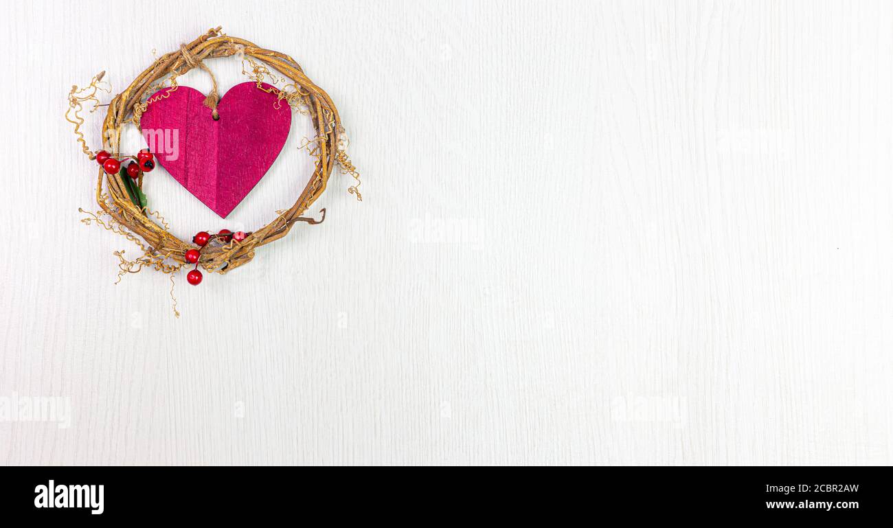 red wooden heart decoration surrounded by twigs and red berries, white wood background Stock Photo