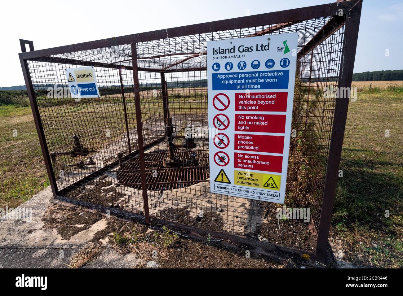 Caged and capped off oil well in Nottinghamshire oil field near Bothamsall with warning sign. Stock Photo