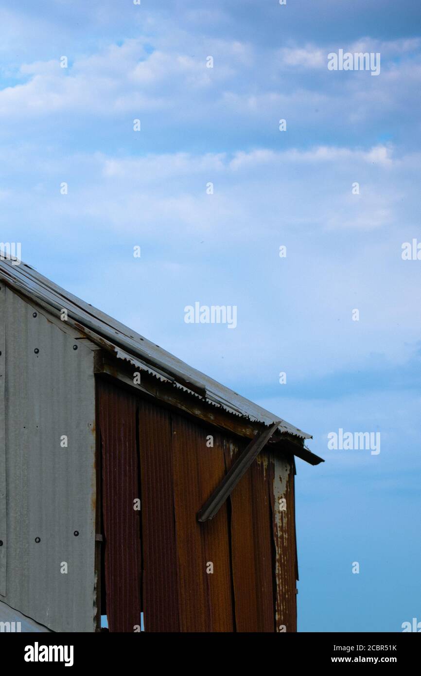 Corrugated iron farm building with red roof in the English countryside in portrait orientation