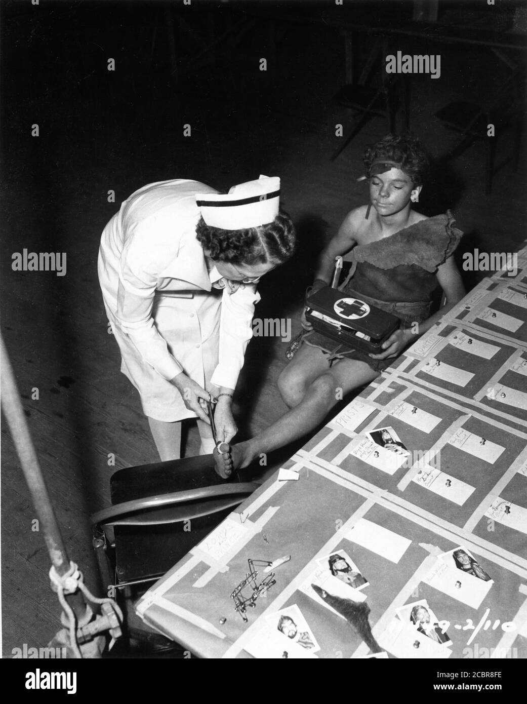 Young RUSS TAMBLYN in costume as Saul receives treatment for injured foot from Studio Nurse on set candid during filming of SAMSON AND DELILAH 1949 director CECIL B. DeMILLE Paramount Pictures Stock Photo