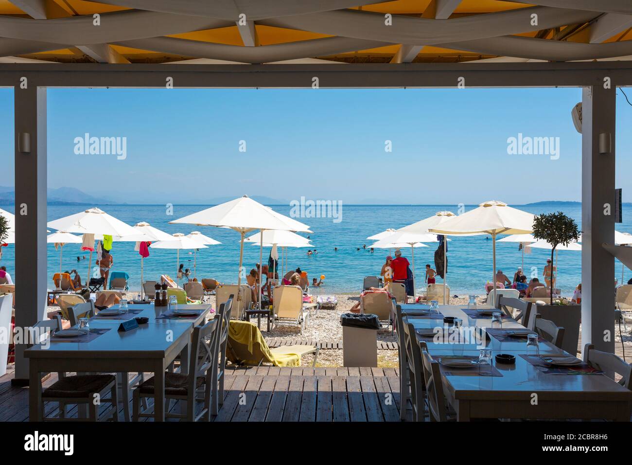 View from inside a seafront taverna looking out at Barbati Beach on the northeast coast of Corfu, Ionian Islands, Greece Stock Photo