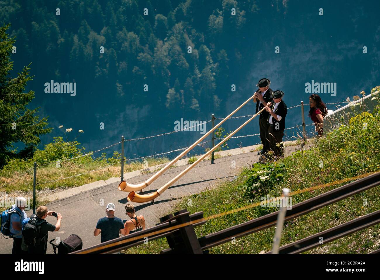 Schynige Platte, Bernese Oberland, Switzerland - August 1 2019 : high angle view on 2 Alpenhorn players in traditional swiss outfit and tourists watch Stock Photo