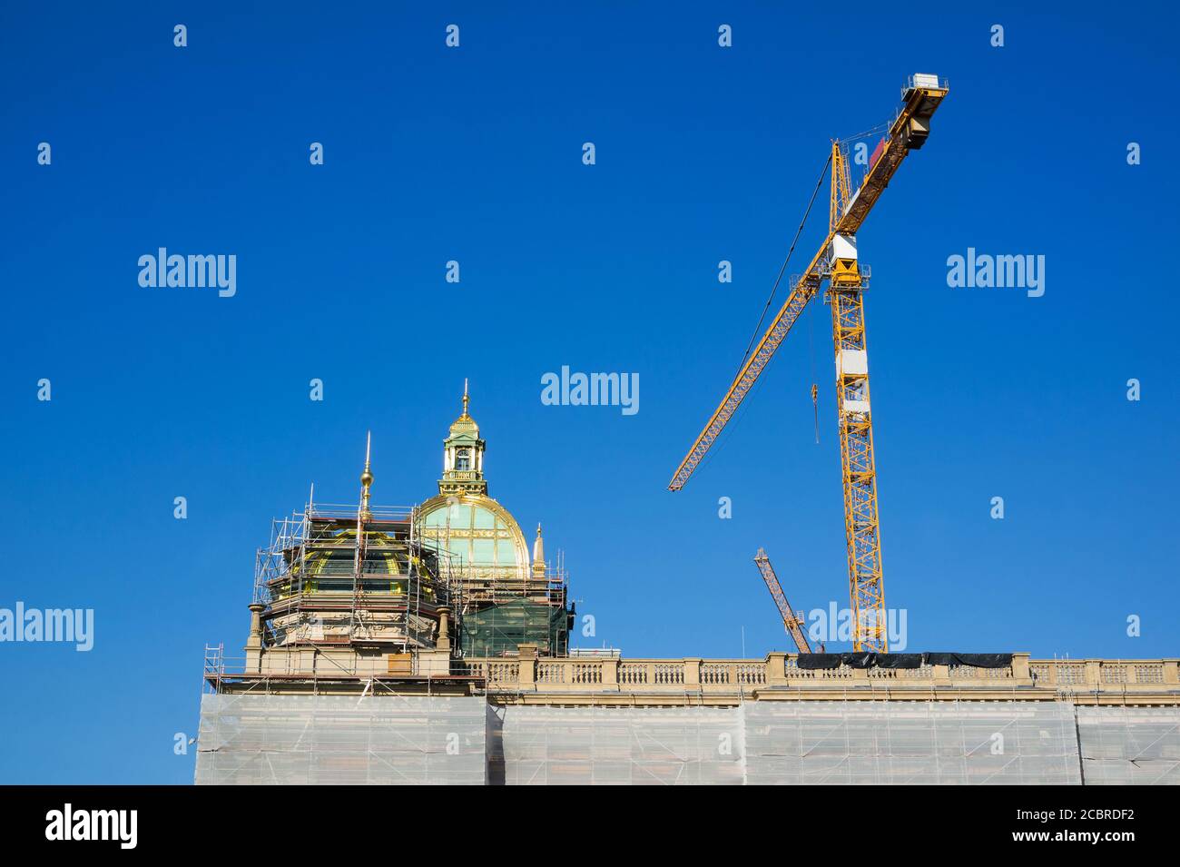 Old historic building with shiny cupola and dome is reconstructed, restored, and renovated. Scaffold and crane is used for reconstruction, renovation Stock Photo