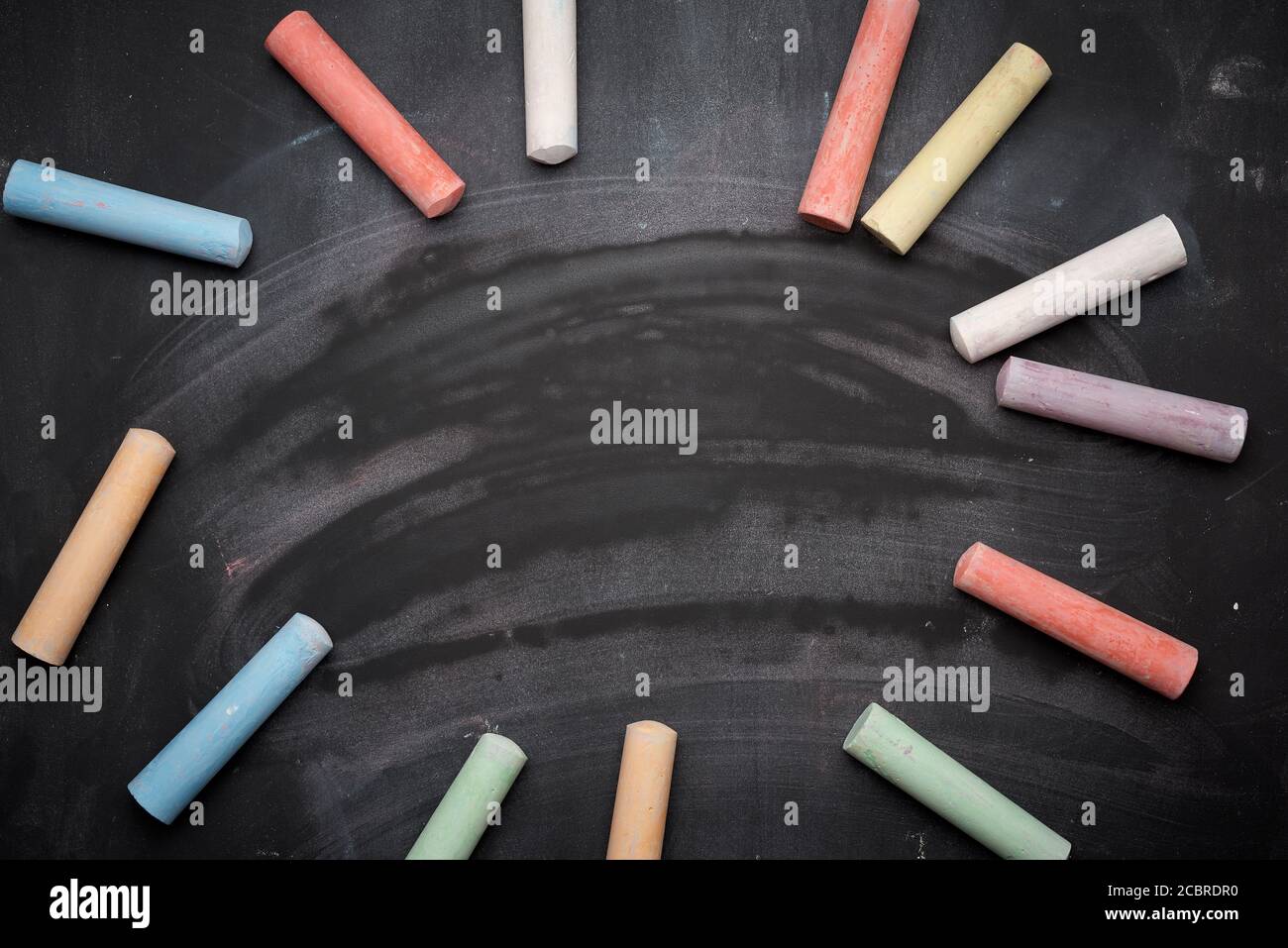 multicolored chalks on lie on empty black chalk board, top view, back ...