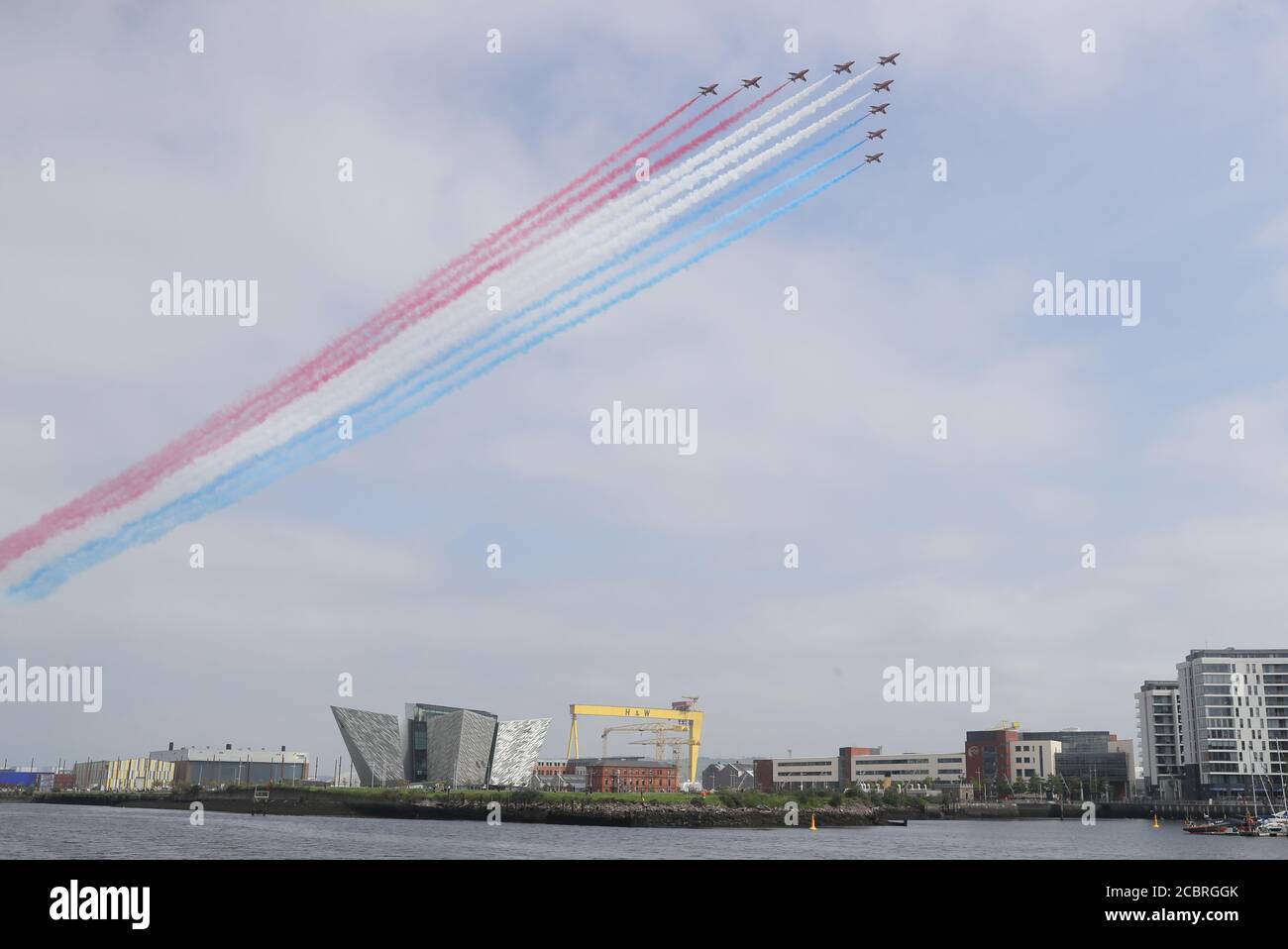 The Red Arrows fly over the Titanic slipway, the Titanic Museum and the Samson and Goliath cranes in Belfast as part of their UK-wide flypast to mark VJ Day. Stock Photo