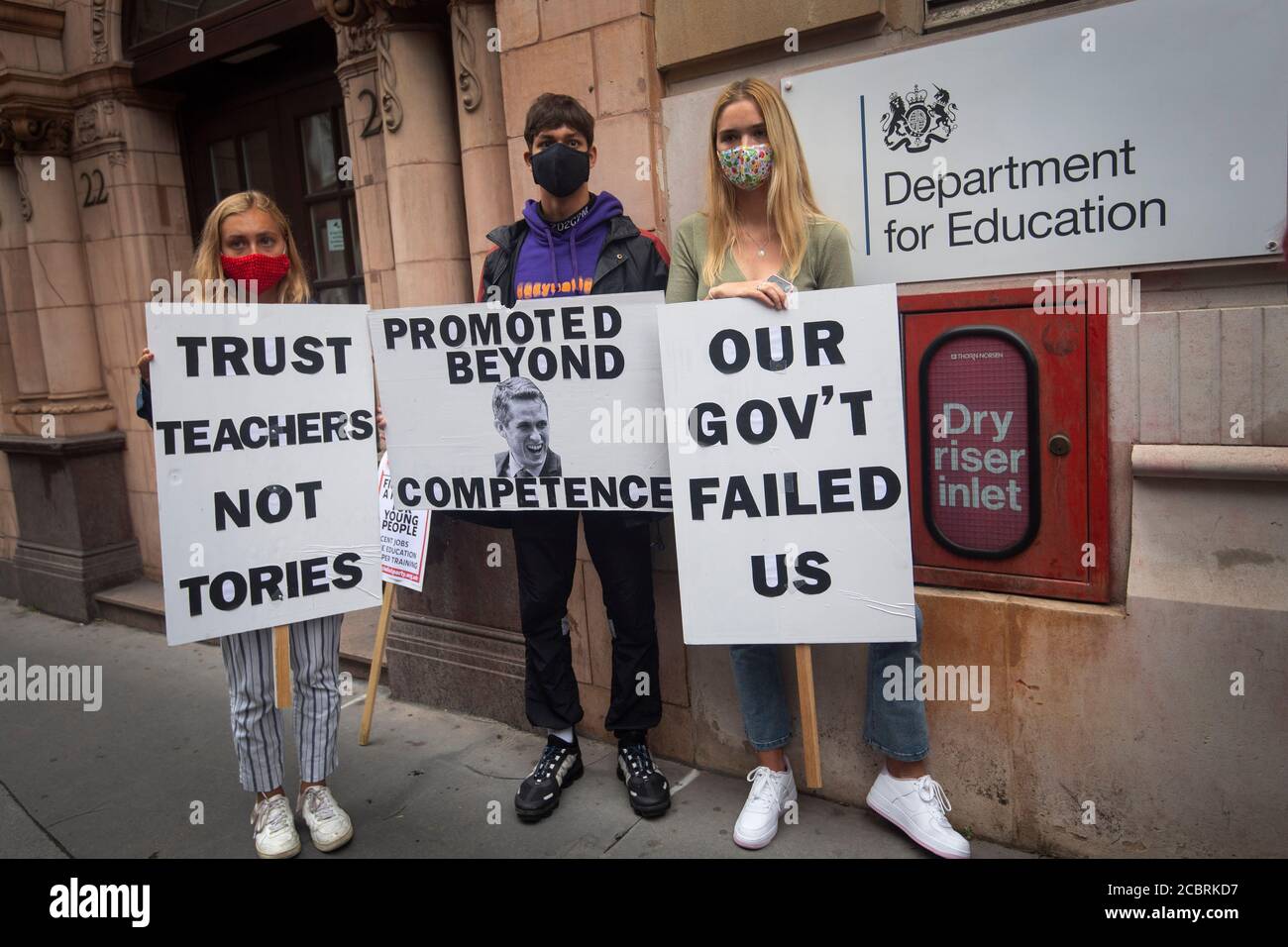 Students wearing face masks take part in a protest outside the Department for Education in Westminster, London over the government's handling of A-level results, university provision and bleak employment prospects. Stock Photo