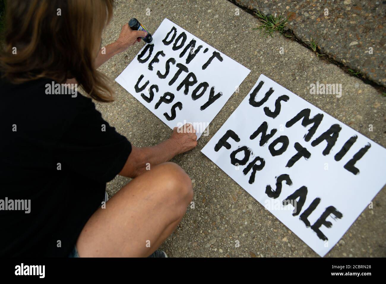 A posters makes signs before marching to the residence of Postmaster General Louis DeJoy - a major Republican donor who President Trump recently nominated to run the United States Postal Service (USPS) despite concerns about conflicts of interest and lack of experience - to demonstrate against Dejoy's changes to the USPS, which many say are acts of sabotage to increase Trump's chances in a mostly vote-by-mail election in Washington, DC, on August 15, 2020, amid the coronavirus pandemic. DeJoy reportedly has invested tens of millions of dollars in direct USPS competitors, and recently he has Stock Photo