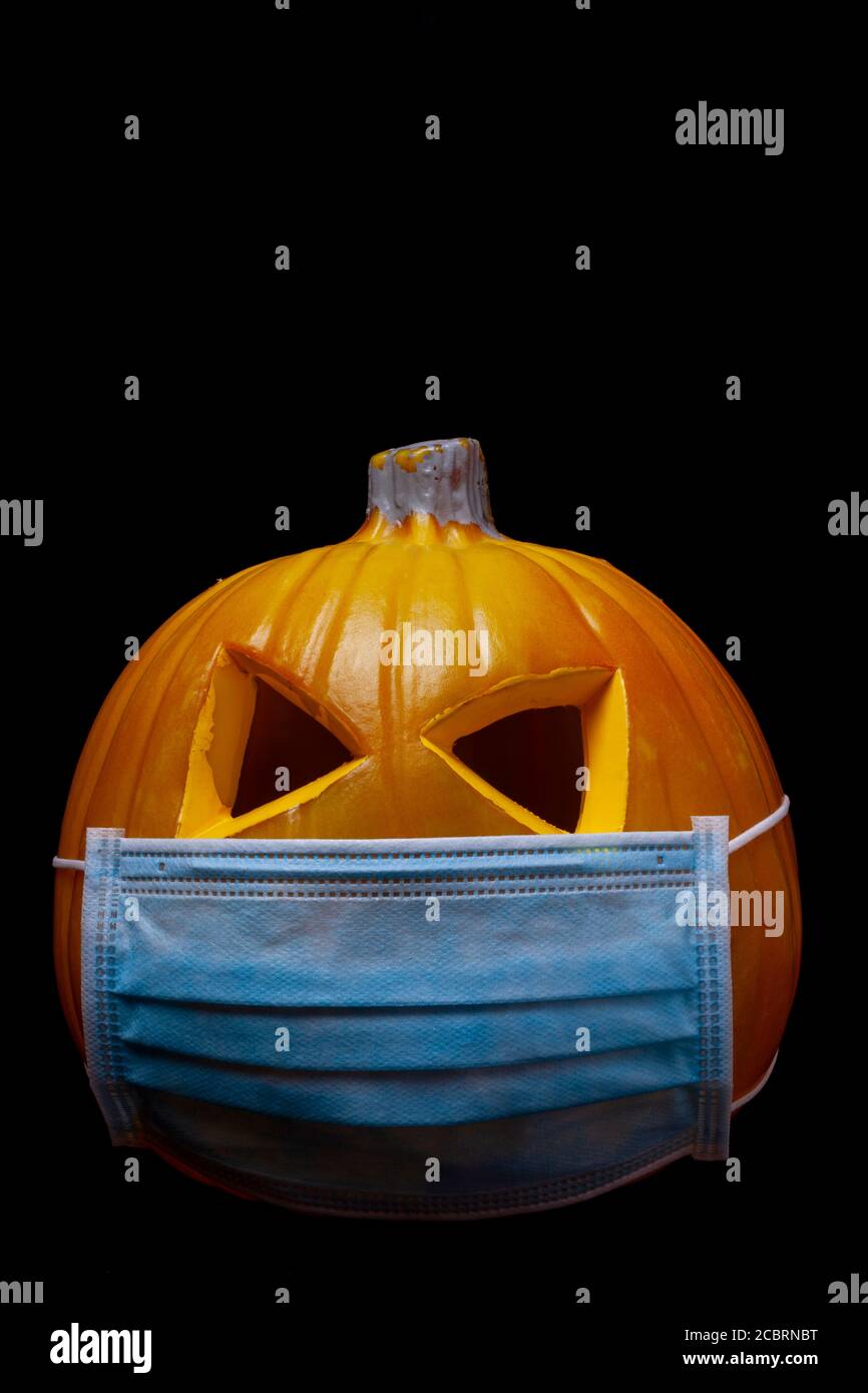 halloween in the age of coronavirus - pumpkin with face mask on black background Stock Photo