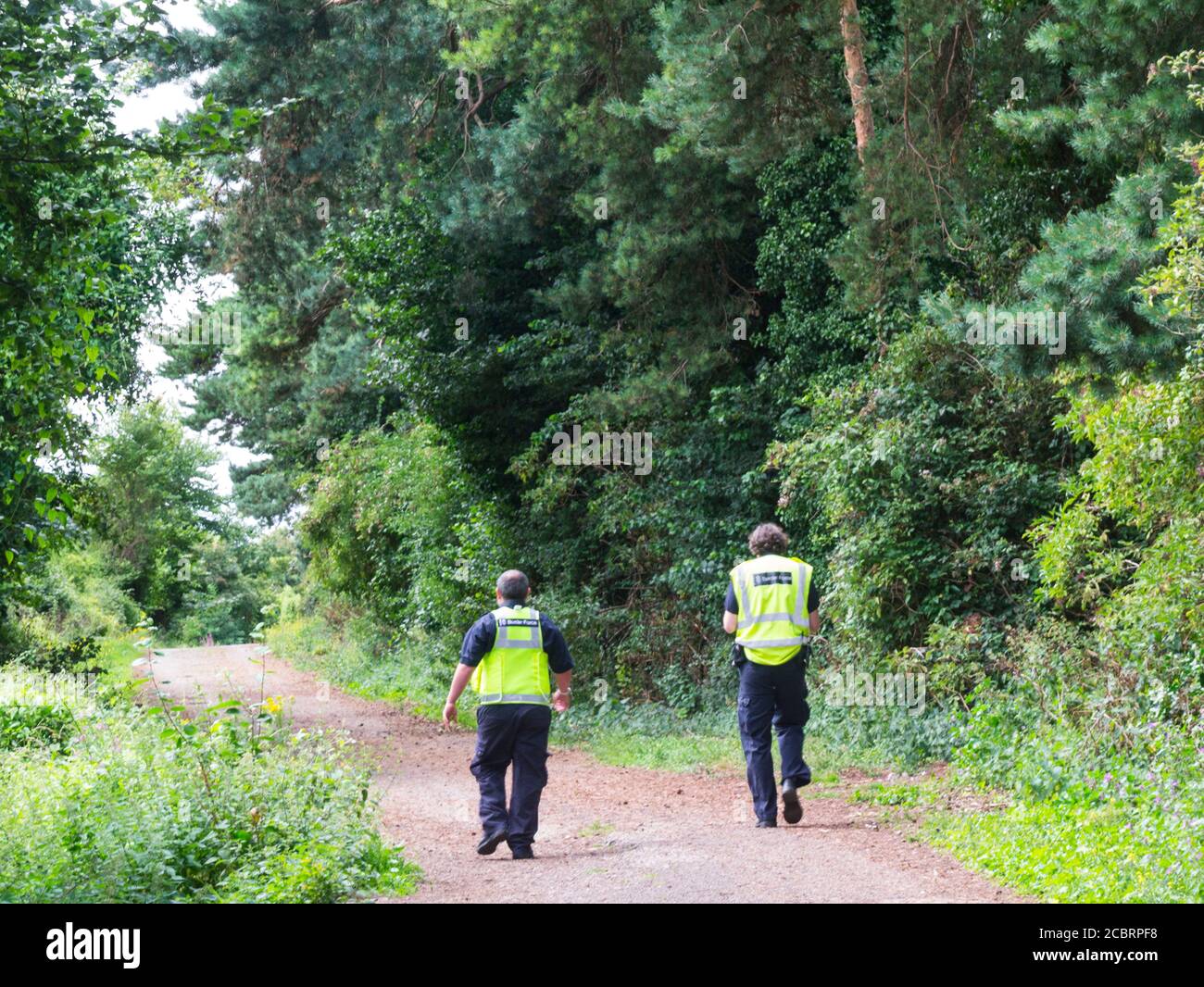 Two Border Force Officers patrolling along footpath bordering River Severn Chepstow Monmouthshire South Wales UK Stock Photo