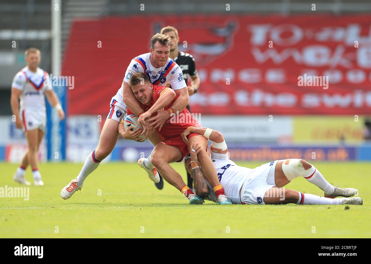 Catalans Dragons' Tom Davies (centre) is tackled by Wakefield Trinity's Romain Navarrete (left) and Matty Ashurst during the Betfred Super League match at The Totally Wicked Stadium, St Helens. Stock Photo