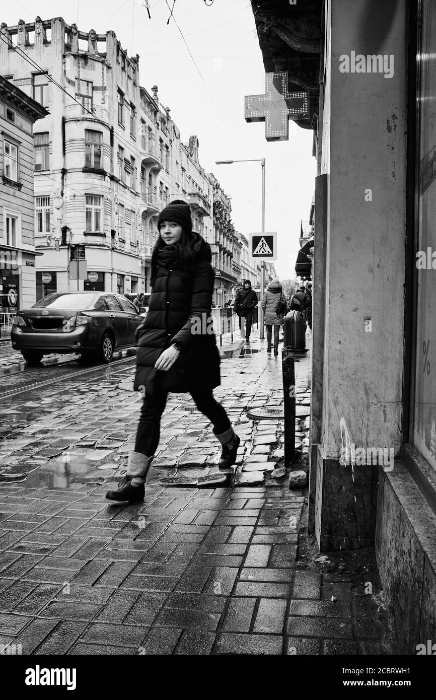 Walking on the sidewalk. Lviv/Ukraine - January 30, 2020: Girl hurries somewhere along the wet sidewalk on Doroshenka Street. Stock Photo