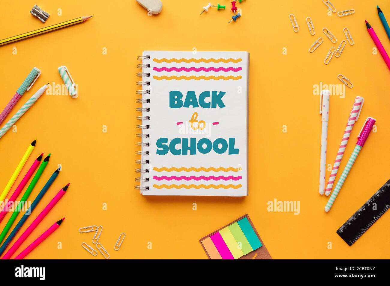 Stock photo of back to school concept with a notebook with lettering and some stationery objects on a yellow background Stock Photo