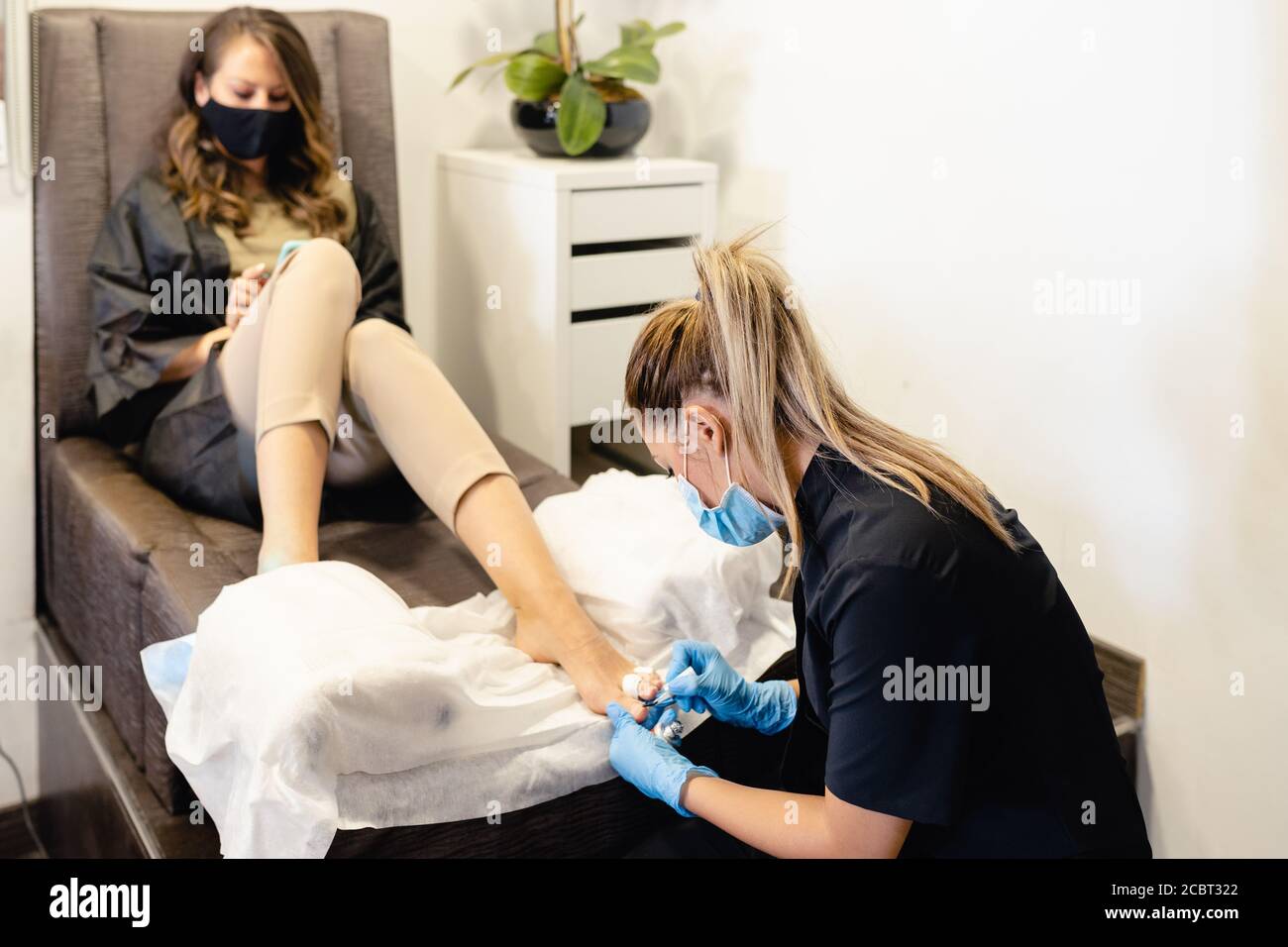 Beautician giving a pedicure filing the nails to a client in a beauty centre. Stock Photo