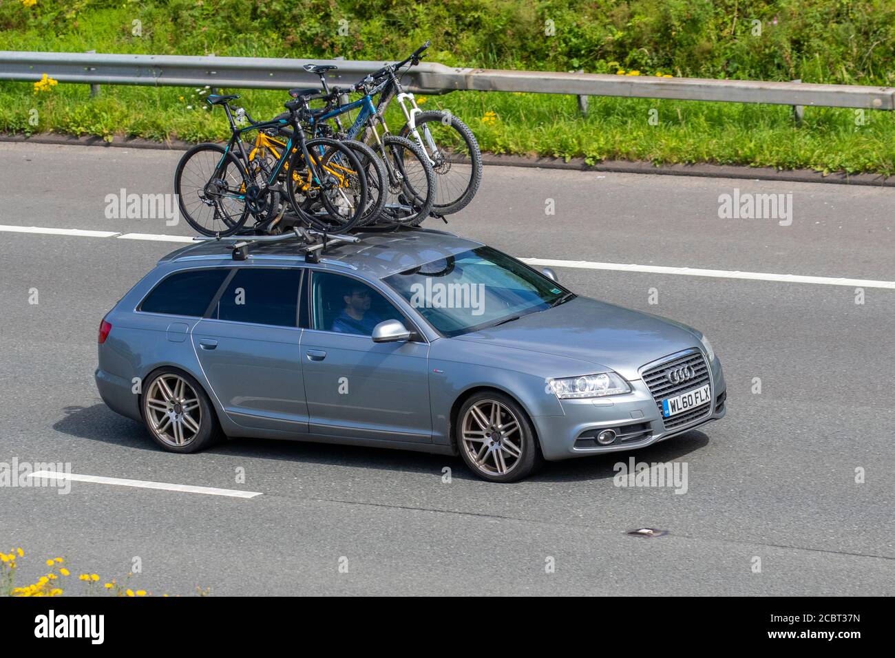 2011 silver Audi A6 S Line Special ED TDI carrying bicycles on roof rack; Vehicular traffic moving vehicles, cars driving vehicle on UK roads, motors, motoring on the M6 motorway highway network. Stock Photo