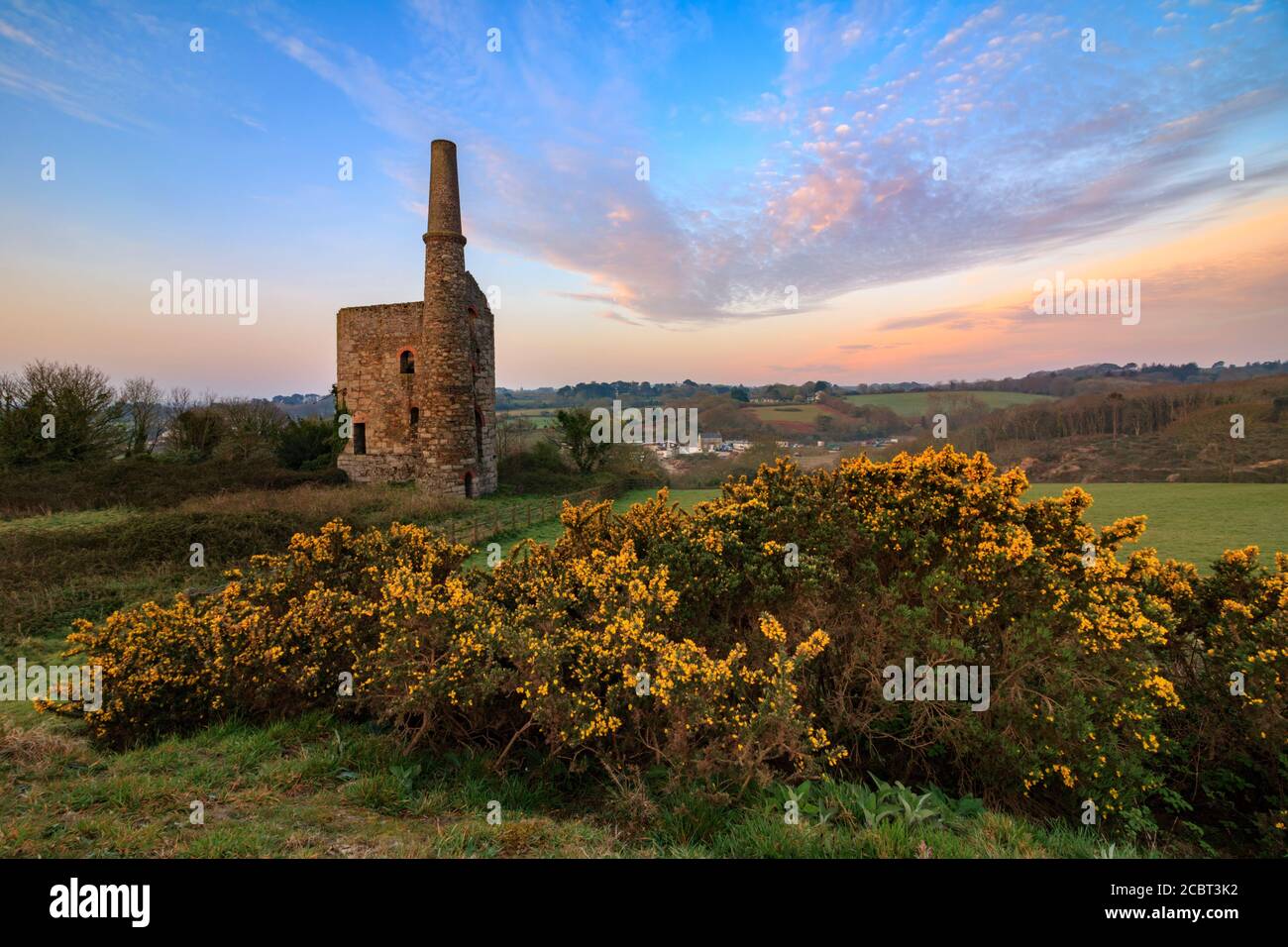 The lower of the two Wheal Unity Wood Engine Houses at Wheal Bush in Cornwall captured at sunrise with gorse in the foreground. Stock Photo