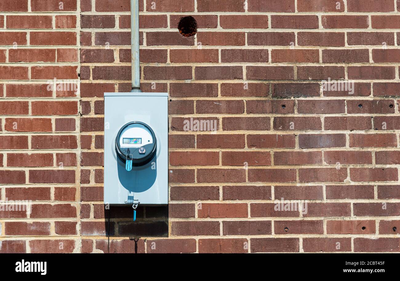 Horizontal shot of a commercial electric meter on an old red brick wall with copy space. Stock Photo