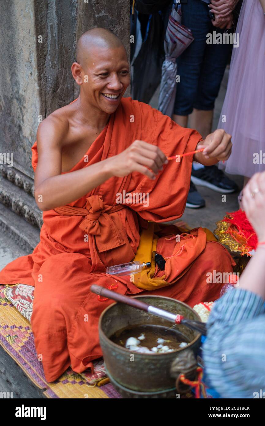 Siem Reap, Cambodia, Angkor Wat - April 21 2019. Buddhist monk smiling and  giving a sai sin bracelet. The sai sin is supposed to provide protection  Stock Photo - Alamy