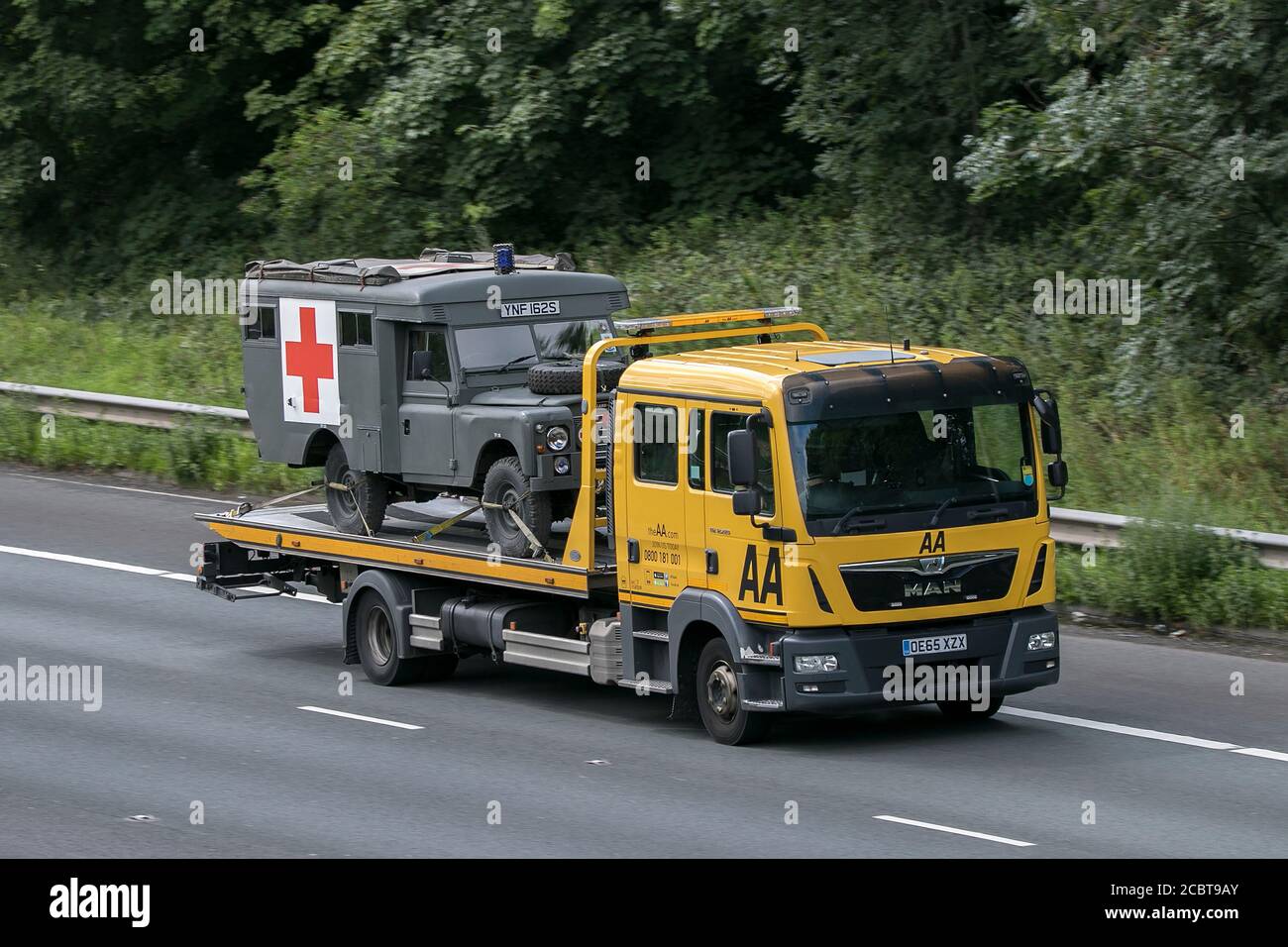 AA Van recovery truck carrying 1997 Land Rover Military Army ambulance driving on the M6 motorway near Preston in Lancashire, UK. Stock Photo