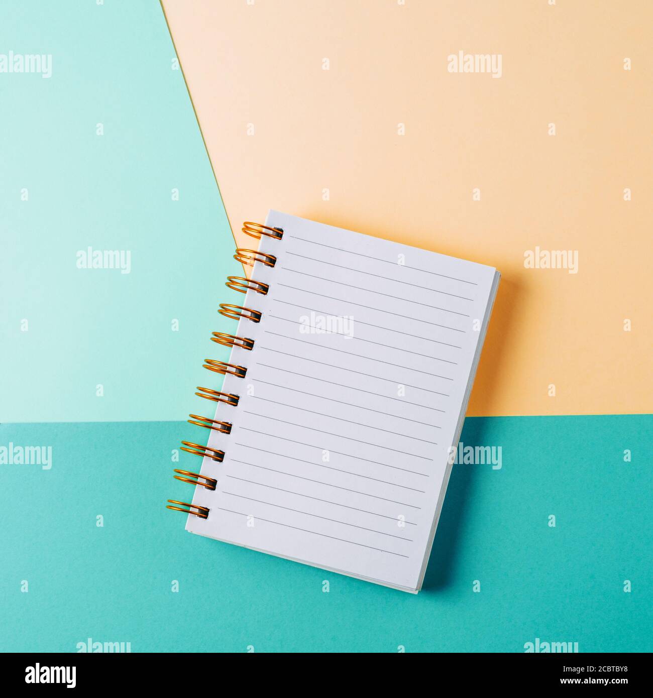 Open notebook with blank sheet and golden spiral on a colorful pastel background. The concept of education, writing down ideas, plans. Place for text. Stock Photo