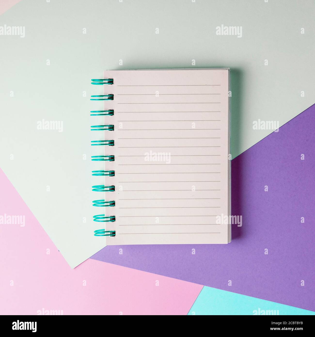 Open notebook with blank sheet and blue spiral on a colorful pastel background. The concept of education, writing down ideas, plans. Place for text. M Stock Photo