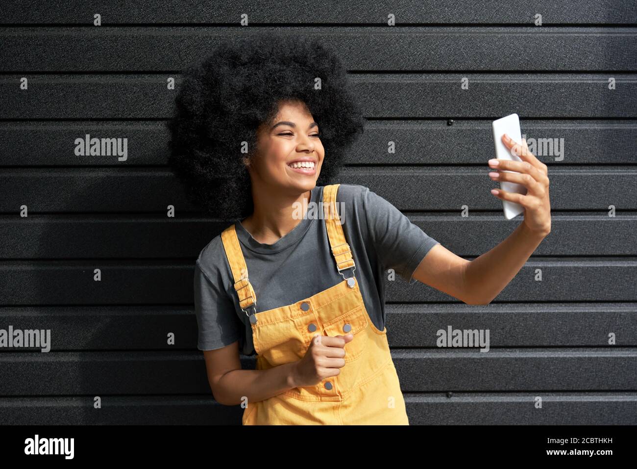 Happy African girl blogger holding smartphone shooting vlog or video calling. Stock Photo