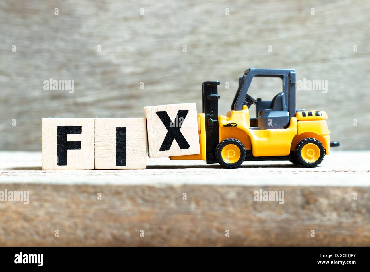 Toy forklift hold letter block x to complete word fix on wood background Stock Photo