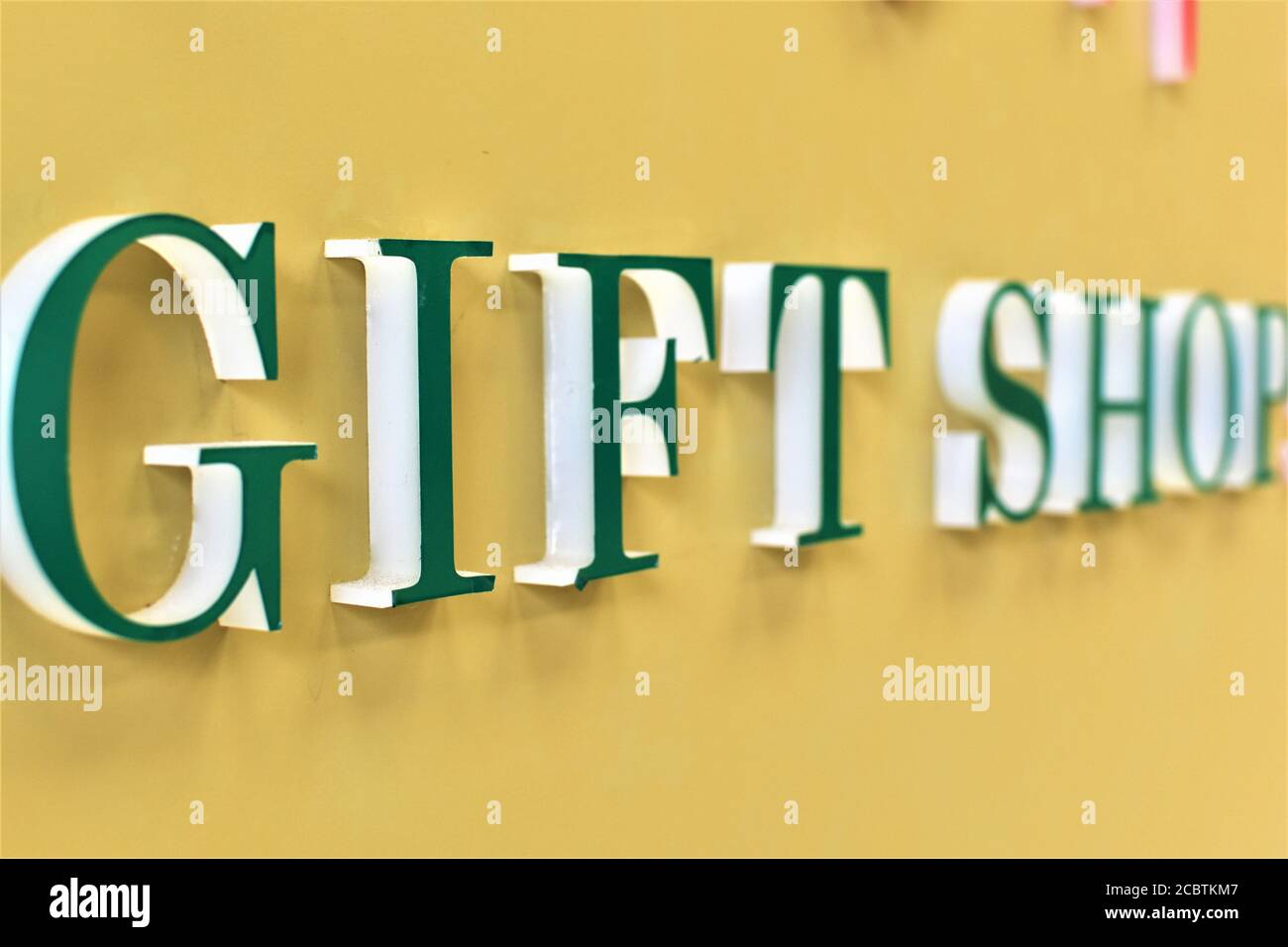 Green bold Giftshop signage on a yellow wall Stock Photo