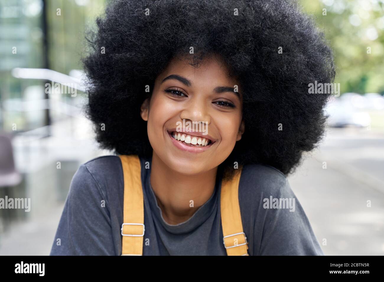 Happy African teen hipster girl with Afro hair looking at camera, headshot. Stock Photo