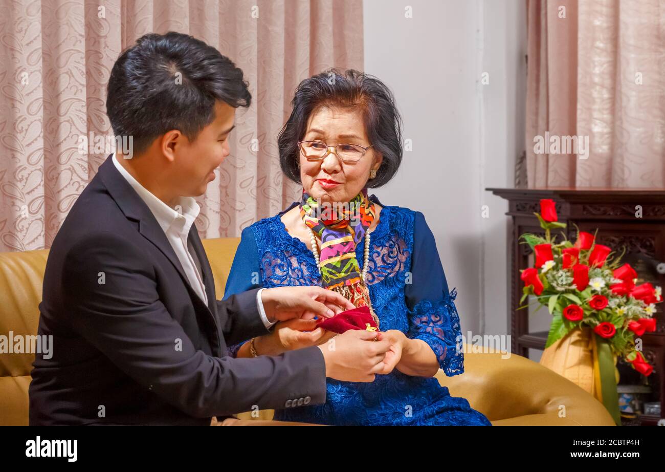 Adult son gives a present to mother on the mothers day Stock Photo