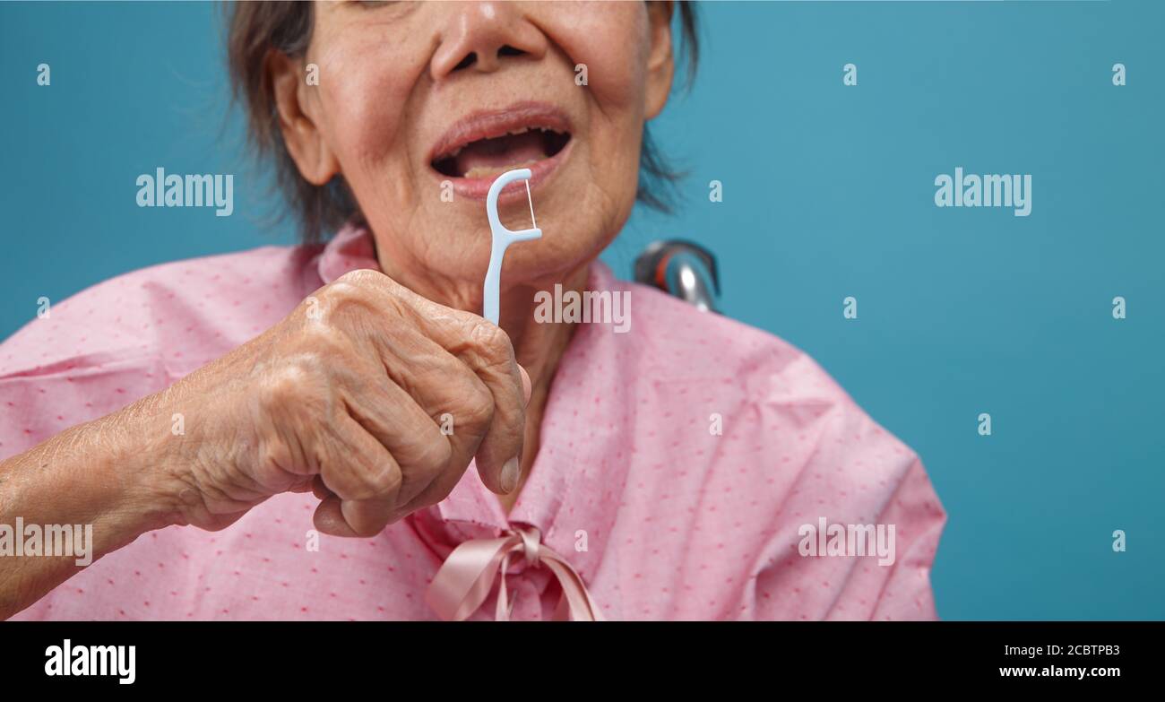 Caregiver take care asian elderly woman while using dental fross stick. Stock Photo