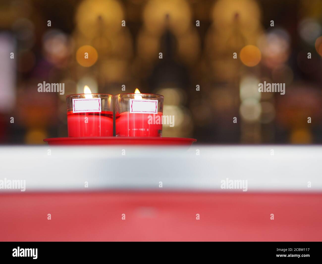 Red candles in clear glass lit on the candle holder at temple
