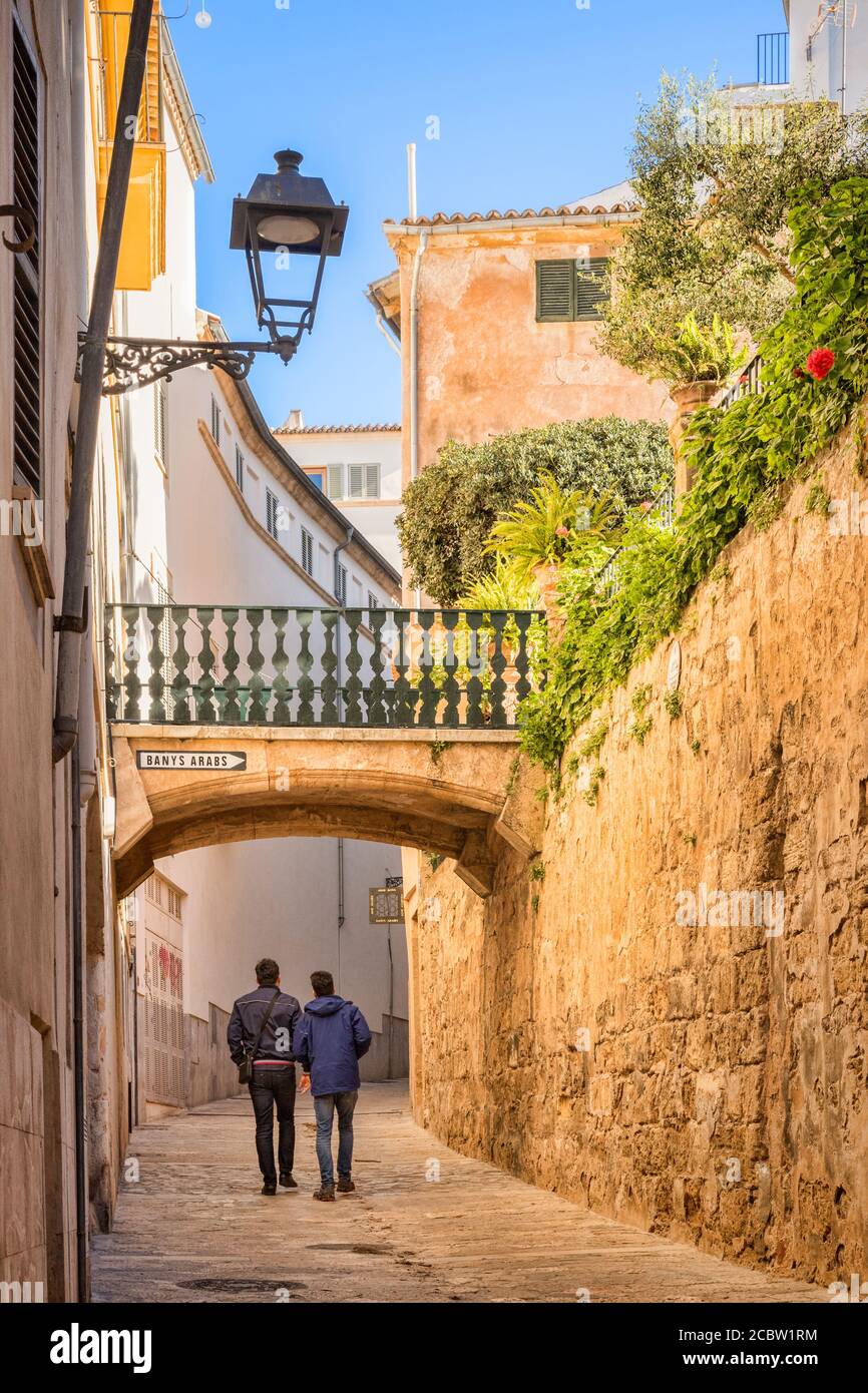 6 March 2020: Palma, Mallorca - Two young men walking up Carrer de Can Serra, past the Arab Baths, in the old quarter of Palma. Stock Photo