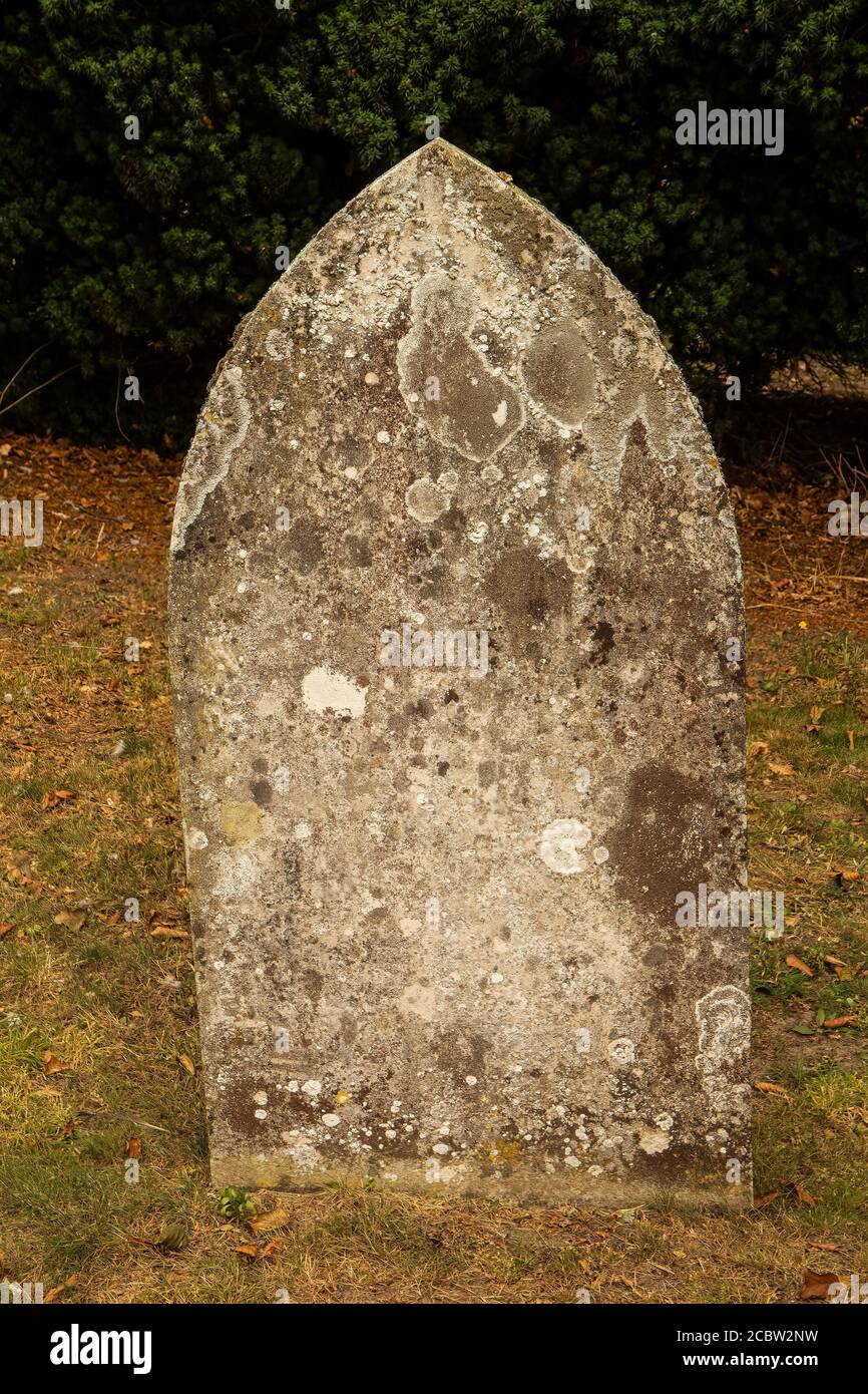 Old weathered arched head stone in church grave yard from late 19th century. Stock Photo