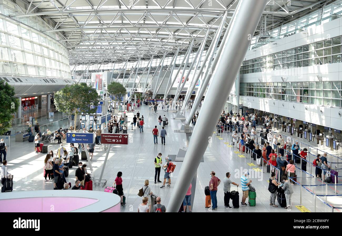 Duesseldorf, Germany. 16th Aug, 2020. Travellers in a long queue wait at Aegean counters at