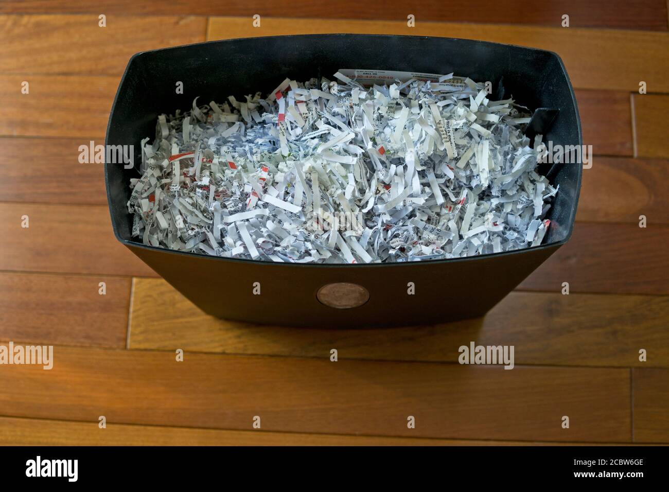 A paper shredder full of shredded paper in a home office. Stock Photo