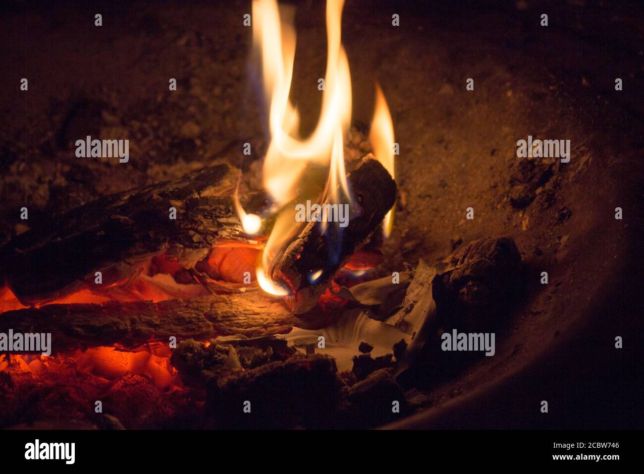 Fire flames and red-hot wooden logs in the dark Stock Photo