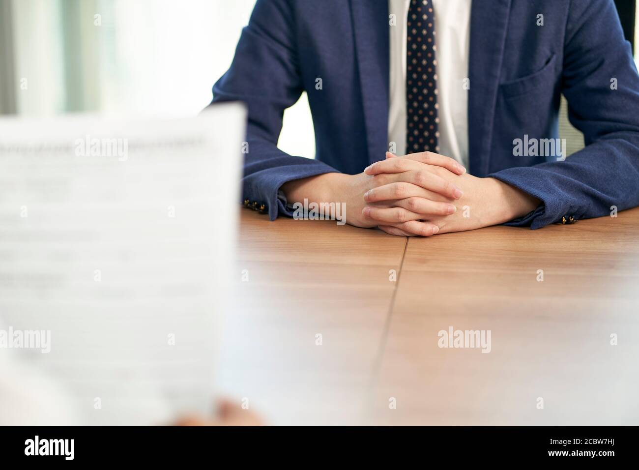 asian job seeker being interviewed by human resources manager in office, focus on hands of the candidate Stock Photo