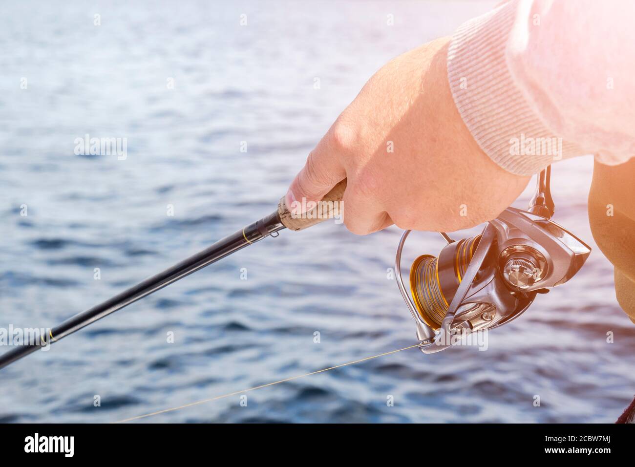 Closeup of a reel fishing rod on a prop and water background Stock Photo -  Alamy