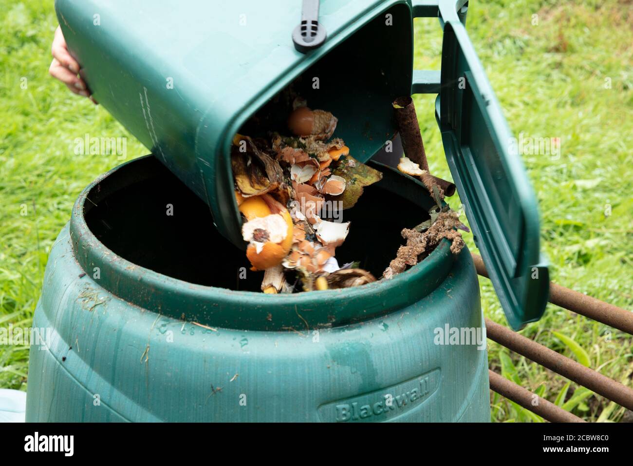 A woman emptying a home composting bin into an outdoor compost bin to