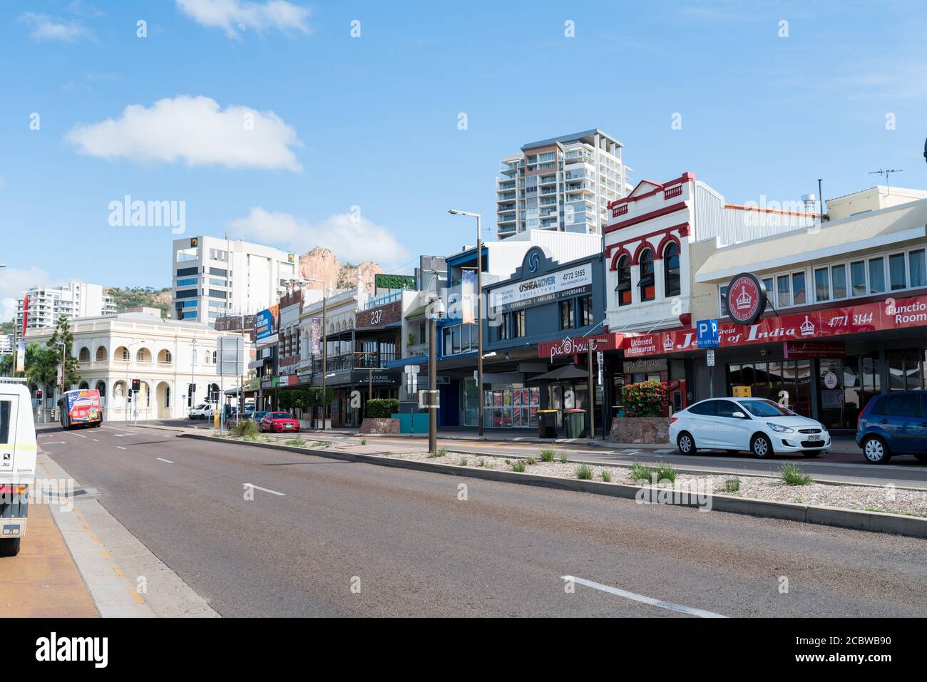 Facades of businesses in Flinders Street, Townsville city center with Castle Hill in the background Stock Photo