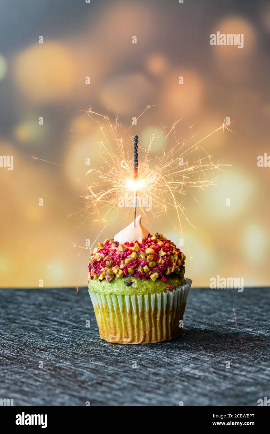 Pistachio cupcake with sparkler lit on, selective focus - celebration concept Stock Photo