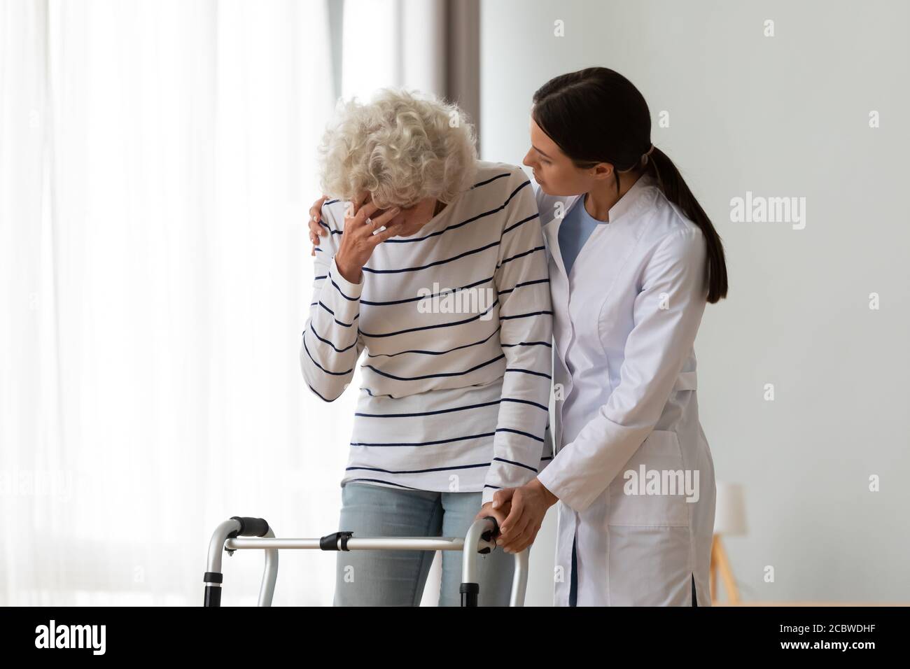 Professional female physiotherapist supporting depressed disabled woman. Stock Photo