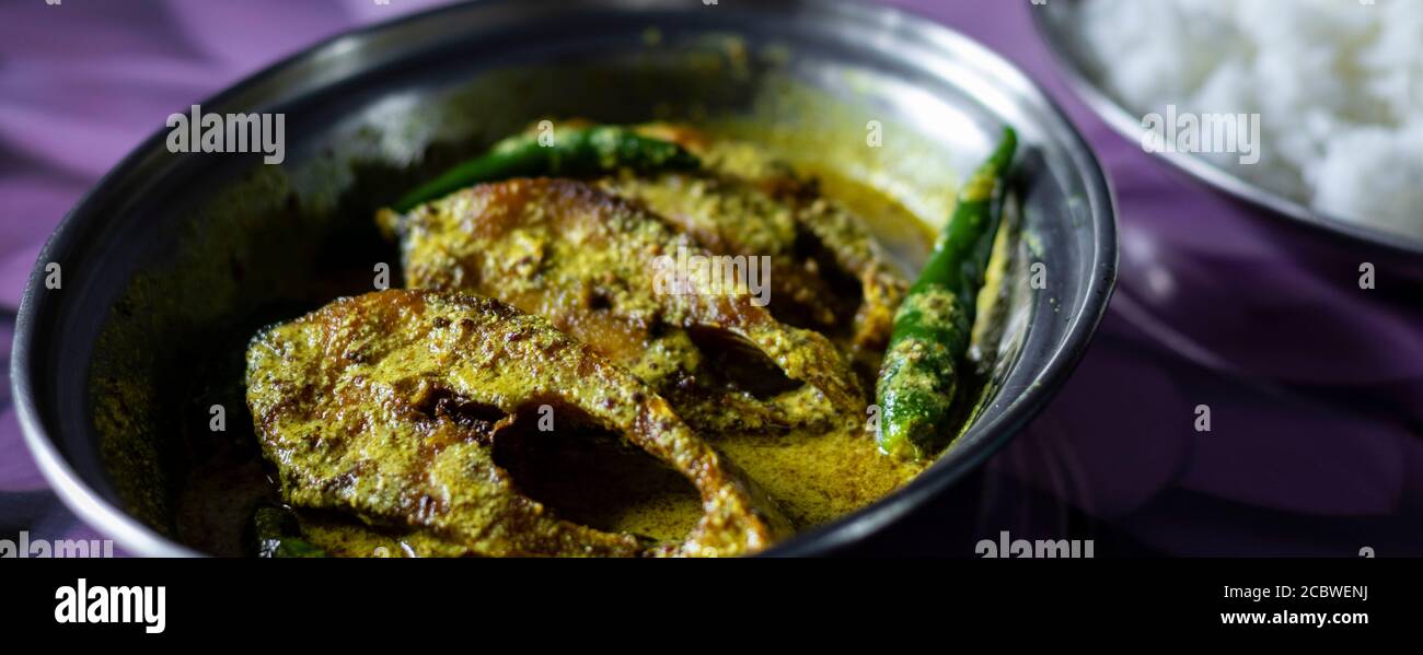 hilsa fish curry with mustard paste and green chilli served on plate along side rice with selective focus Stock Photo