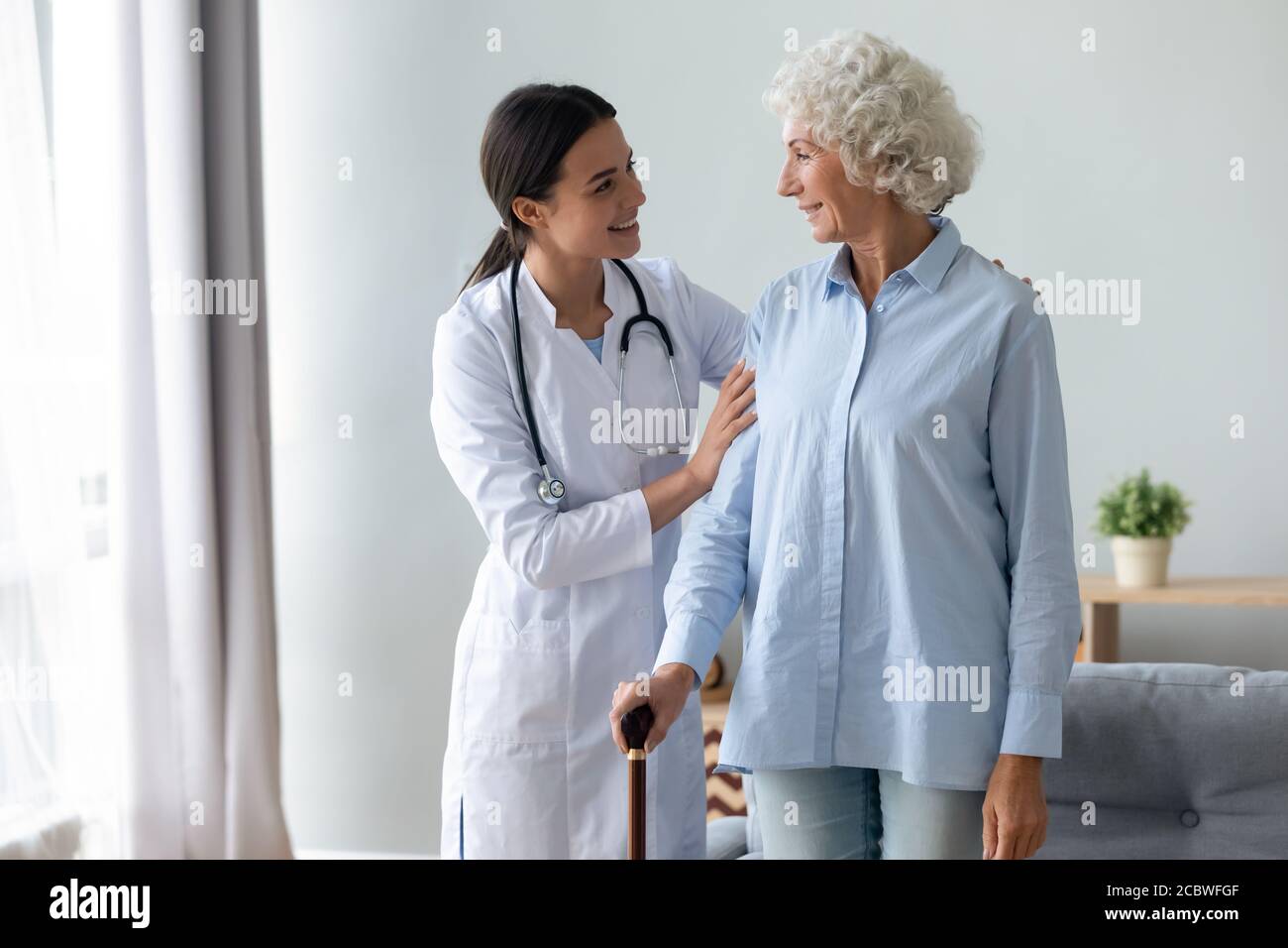 Smiling young physiotherapist starting rehabilitation procedure with elderly patient. Stock Photo