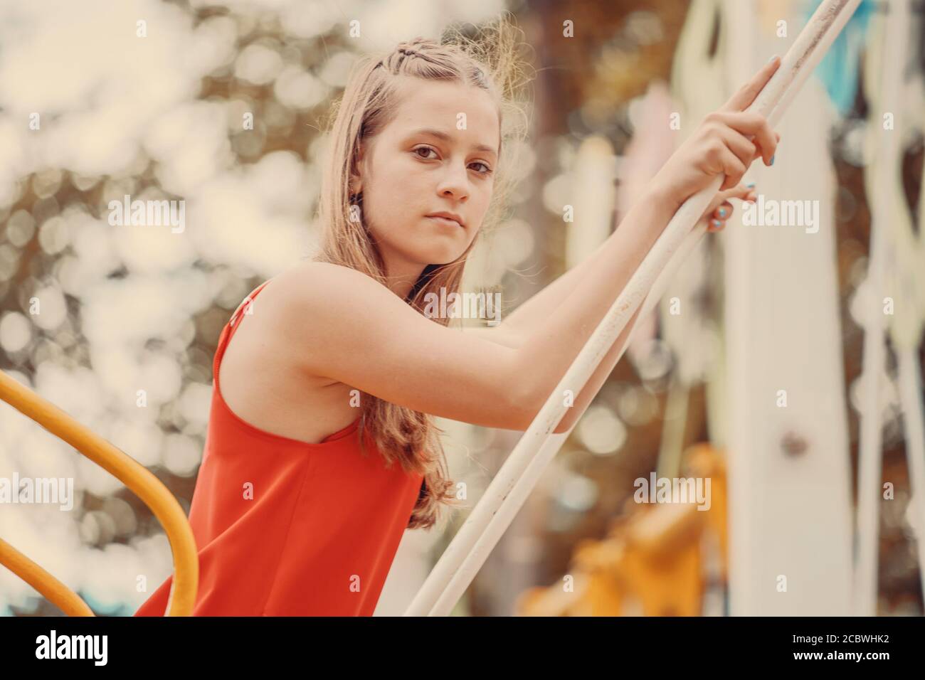 fashionable girl in a red dress on a swing in the park Stock Photo