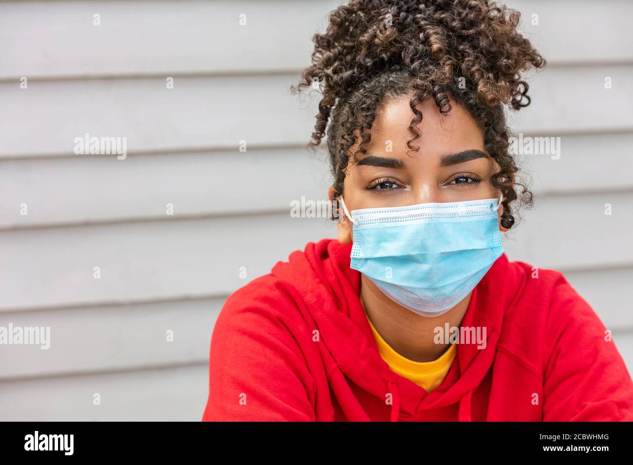 Girl teenager teen mixed race biracial African American female young woman wearing face mask in Coronavirus COVID-19 pandemic Stock Photo