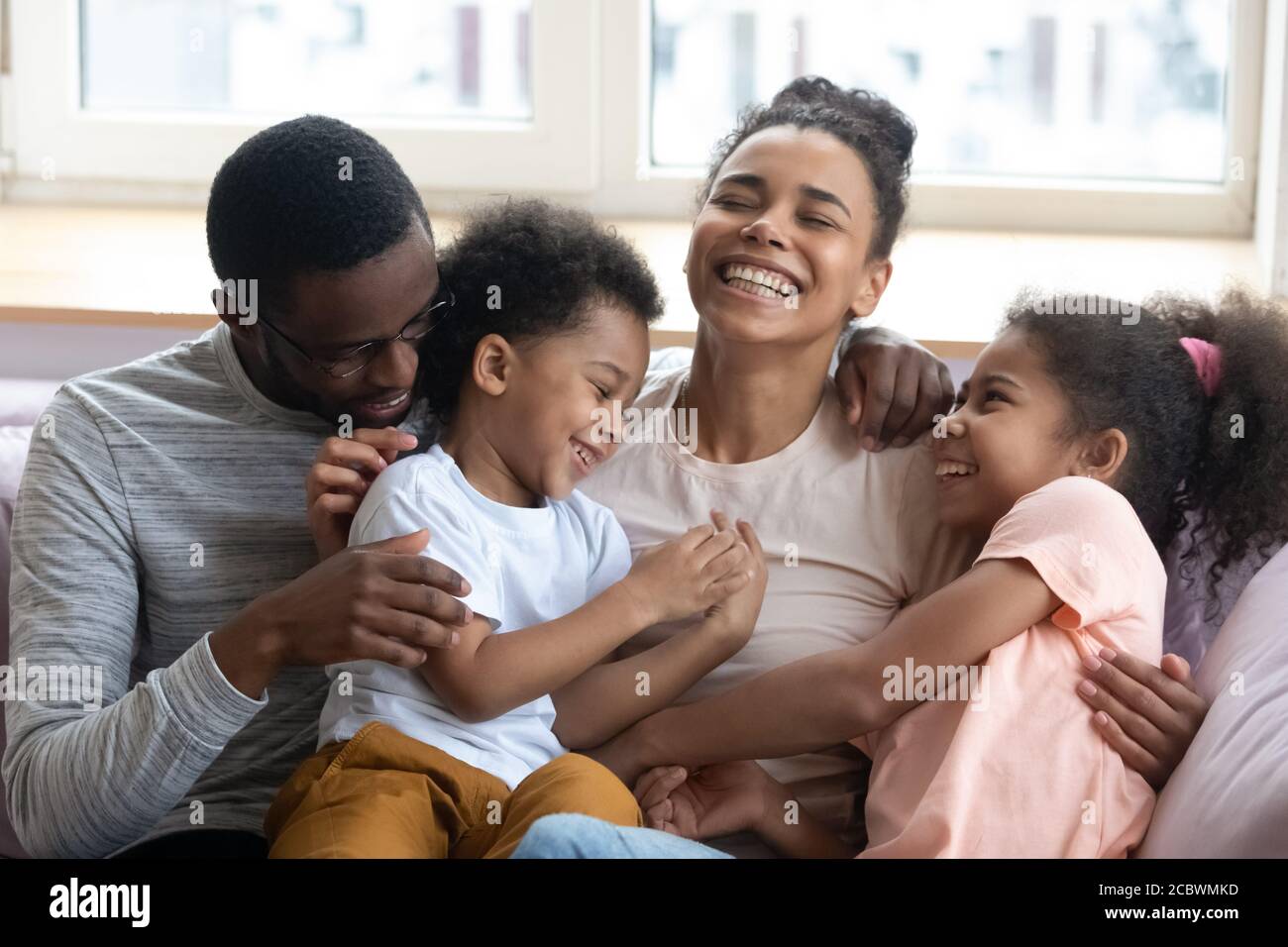 Affectionate black parents tickling and giggling with children at home Stock Photo