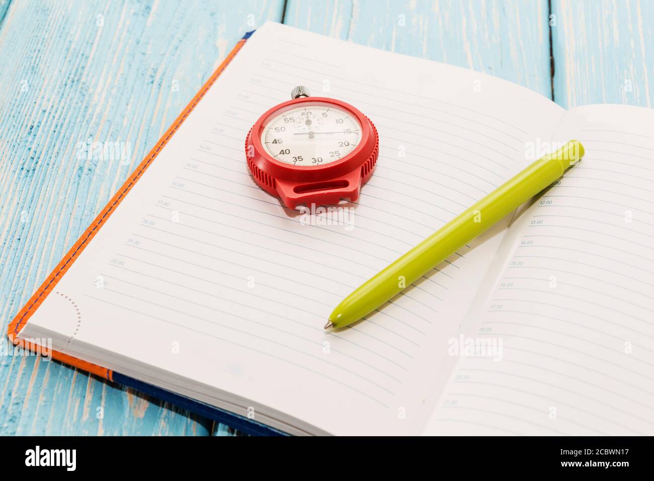 Notepad and stopwatch, on wooden blue background. Stock Photo