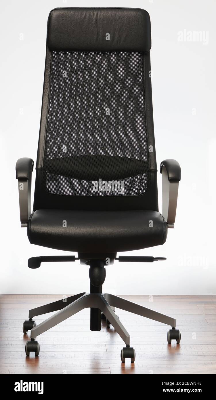 Black office chair on wooden floor on white wall background Stock Photo